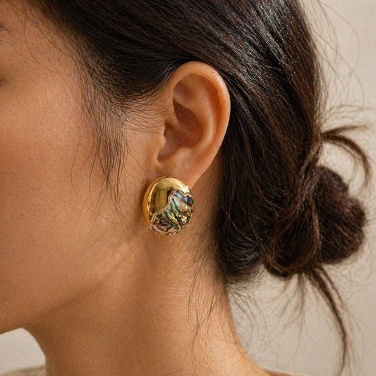 Holograhpic and Gold statement earring worn by a person with a neutral background
