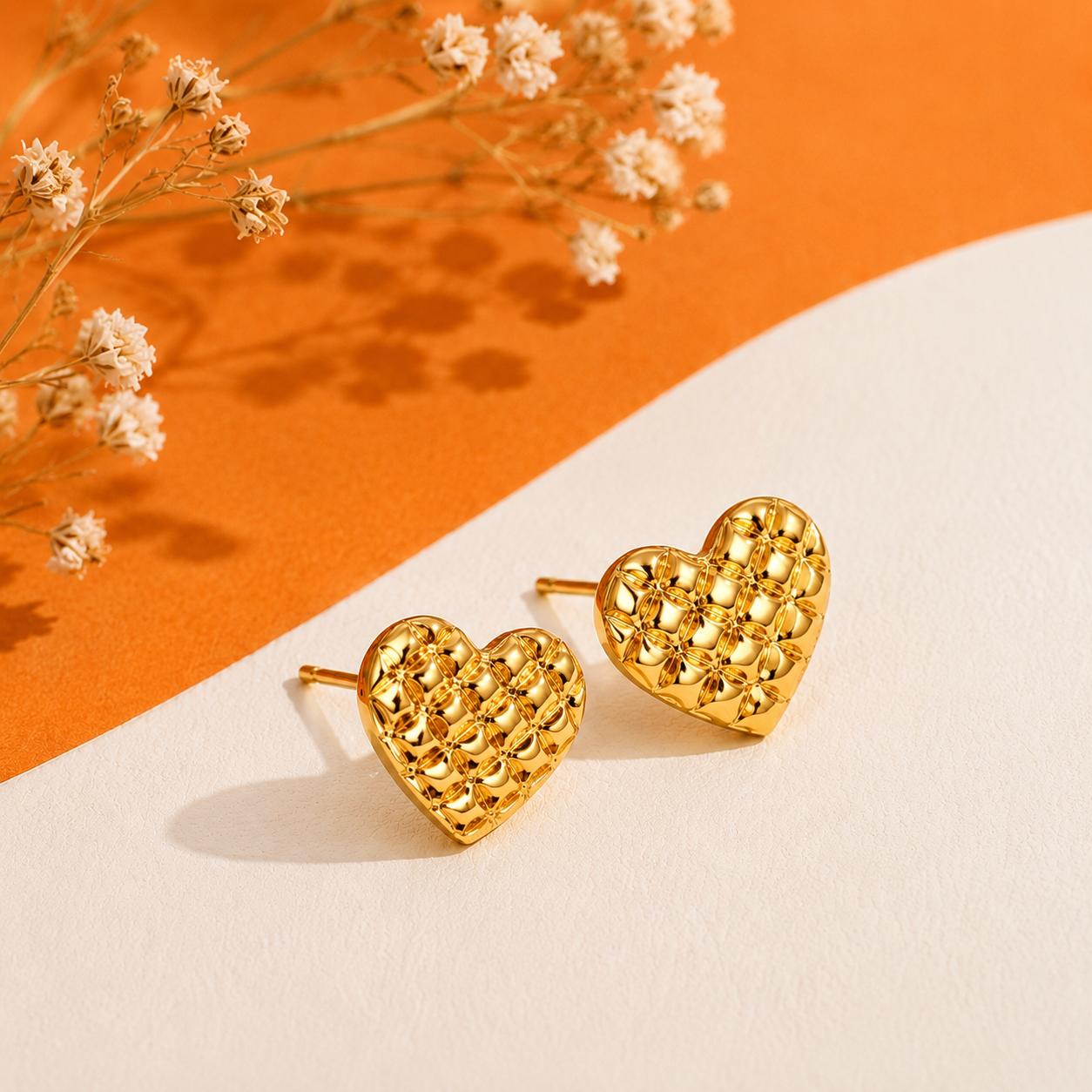 Honey Heart Studs with a sculpted heart design against a warm orange and ivory background.