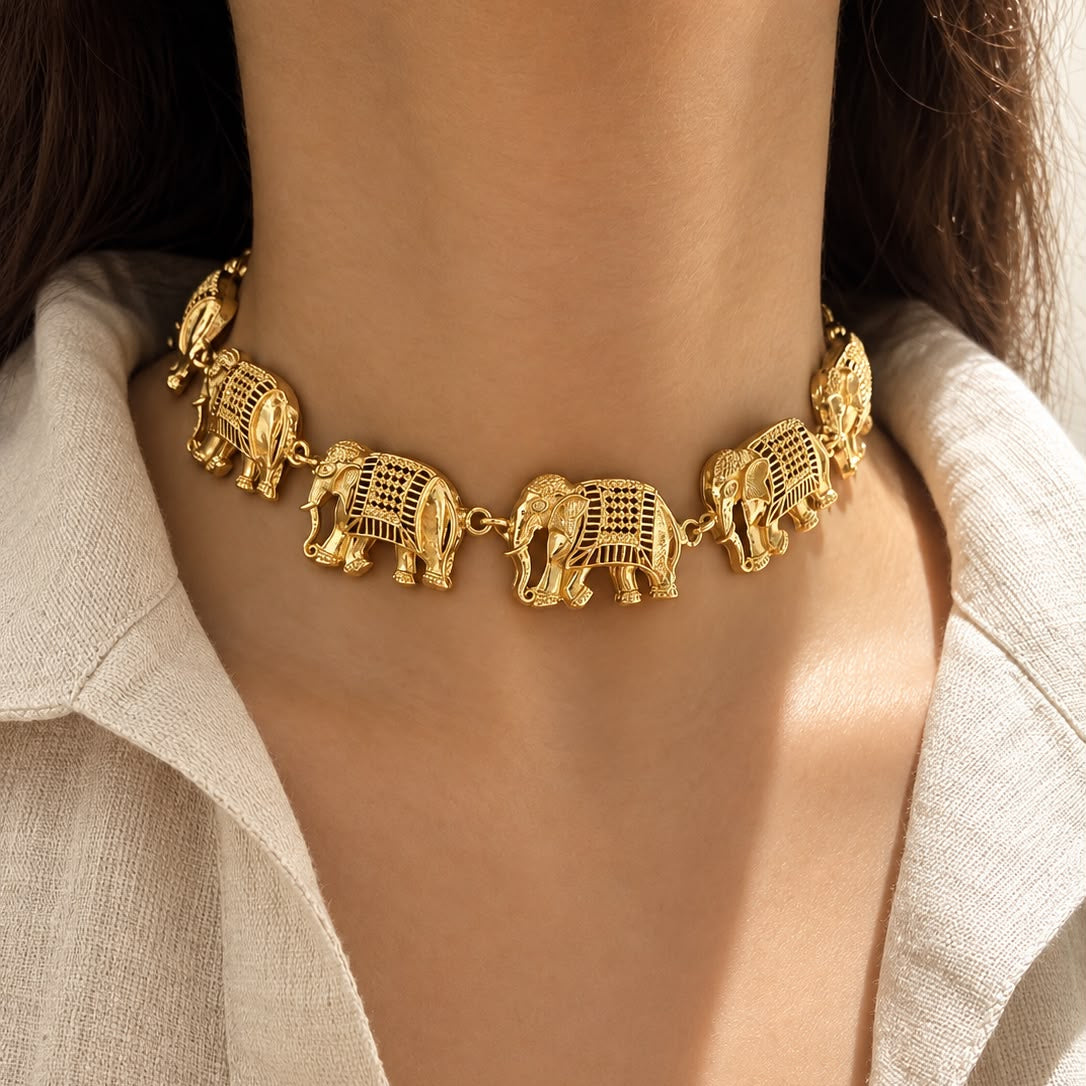 A close-up of a model wearing a gold-toned elephant choker necklace with detailed cutout patterns, paired with a light beige linen shirt.
