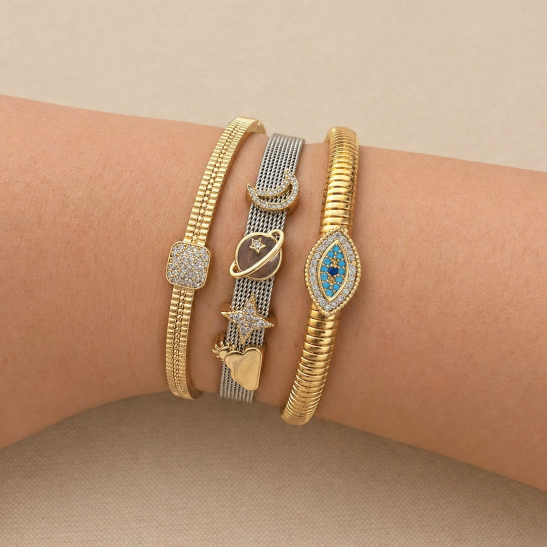 Multiple bracelet featuring different elements, with a focus on the centre bracelet that has a silver band with gold celestial charms

