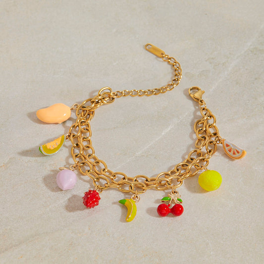 Gold bracelet with colorful fruit-shaped charms on a light background