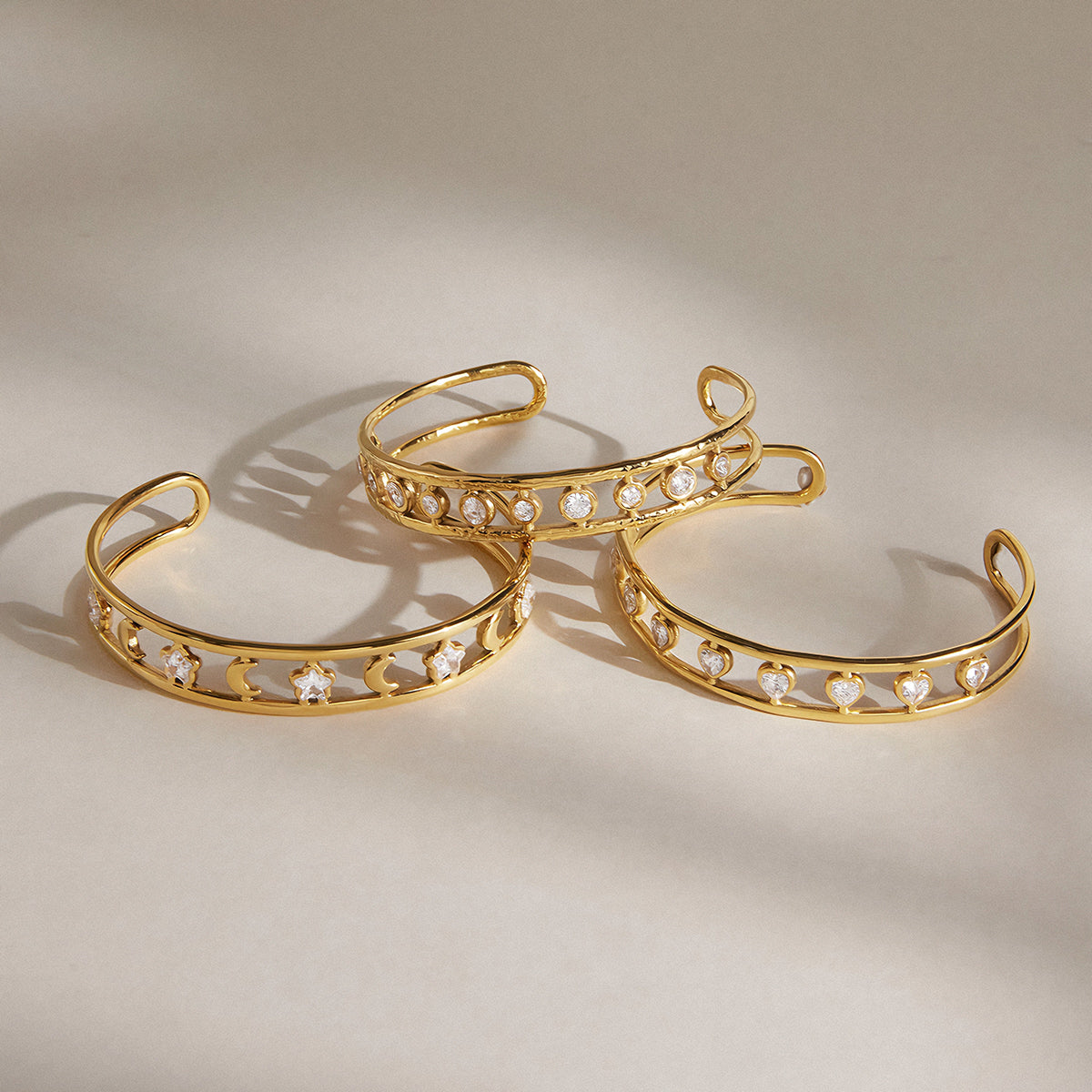 3 Golden bracelet placed together on a cream surface