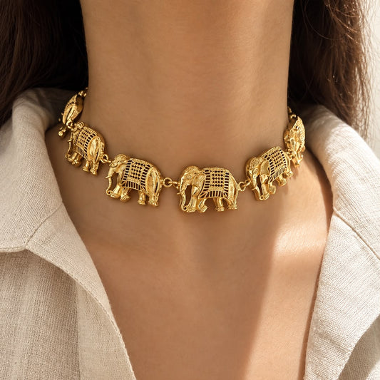 A close-up of a model wearing a gold-toned elephant choker necklace with detailed cutout patterns, paired with a light beige linen shirt.