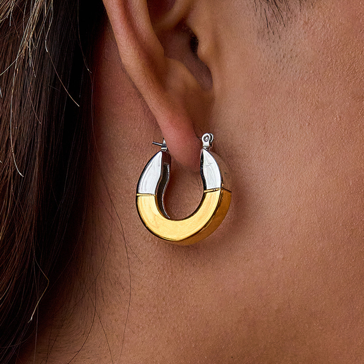 Gold and silver hoop earrings worn by a person 