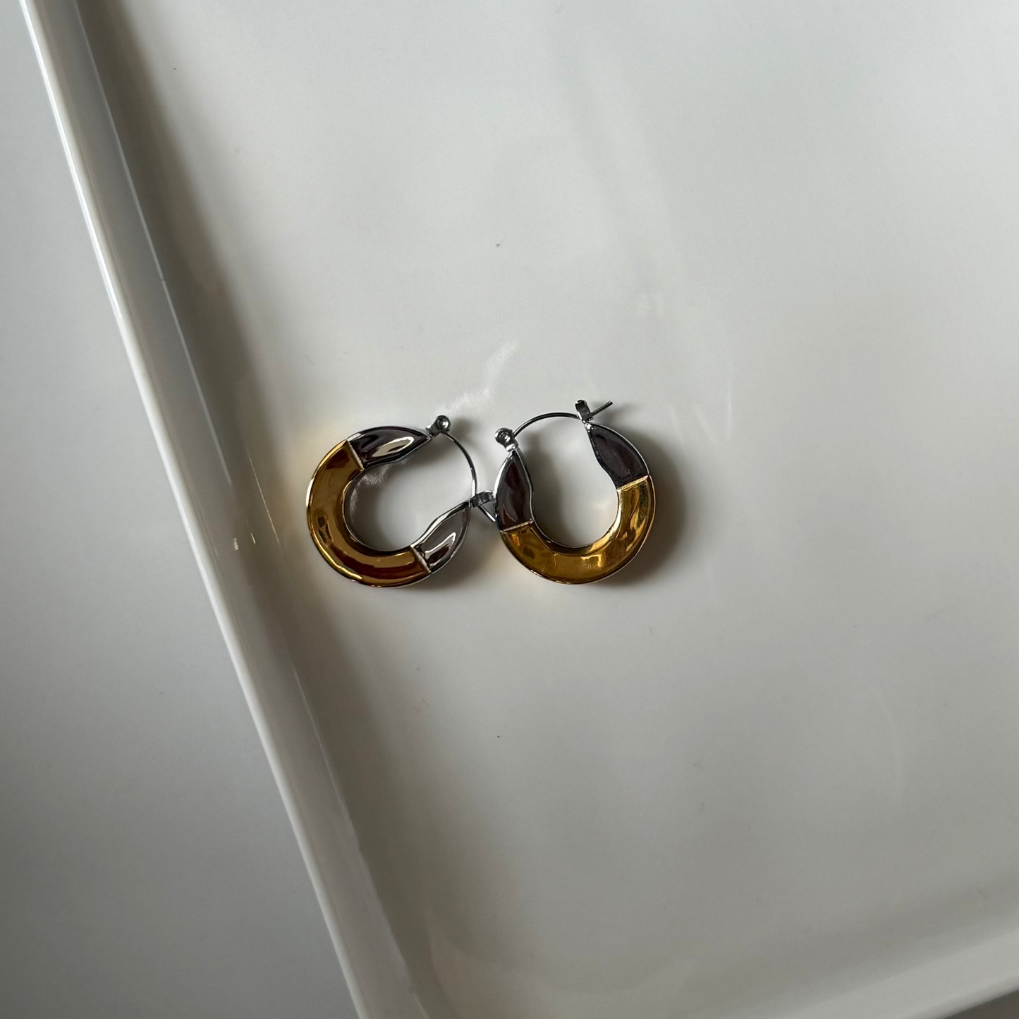 Two toned hybrid loop earrings on a white platter
