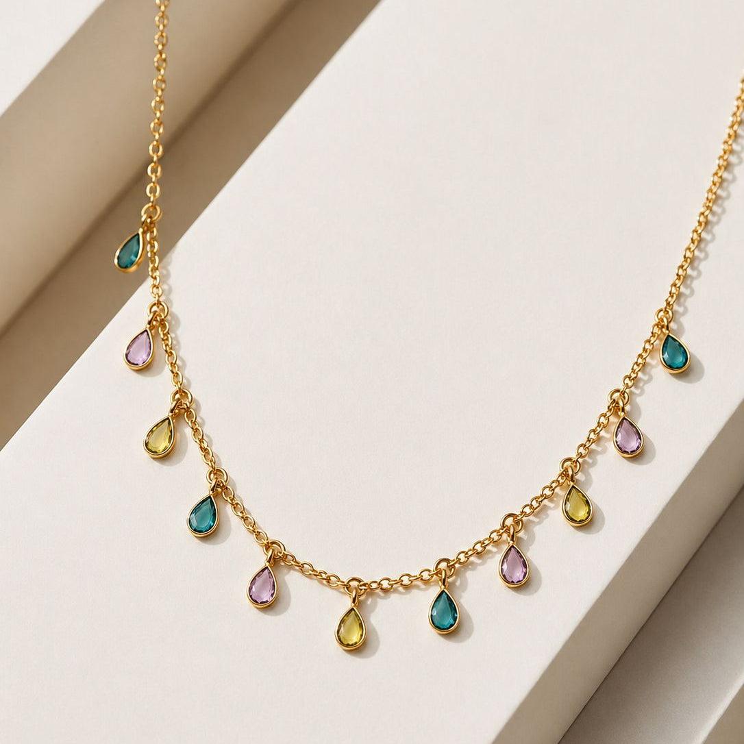 Gold necklace with colorful teardrop-shaped stones on a white surface