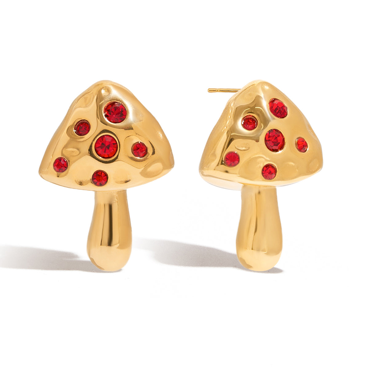 Gold mushroom-shaped earrings with red gemstones on a white background