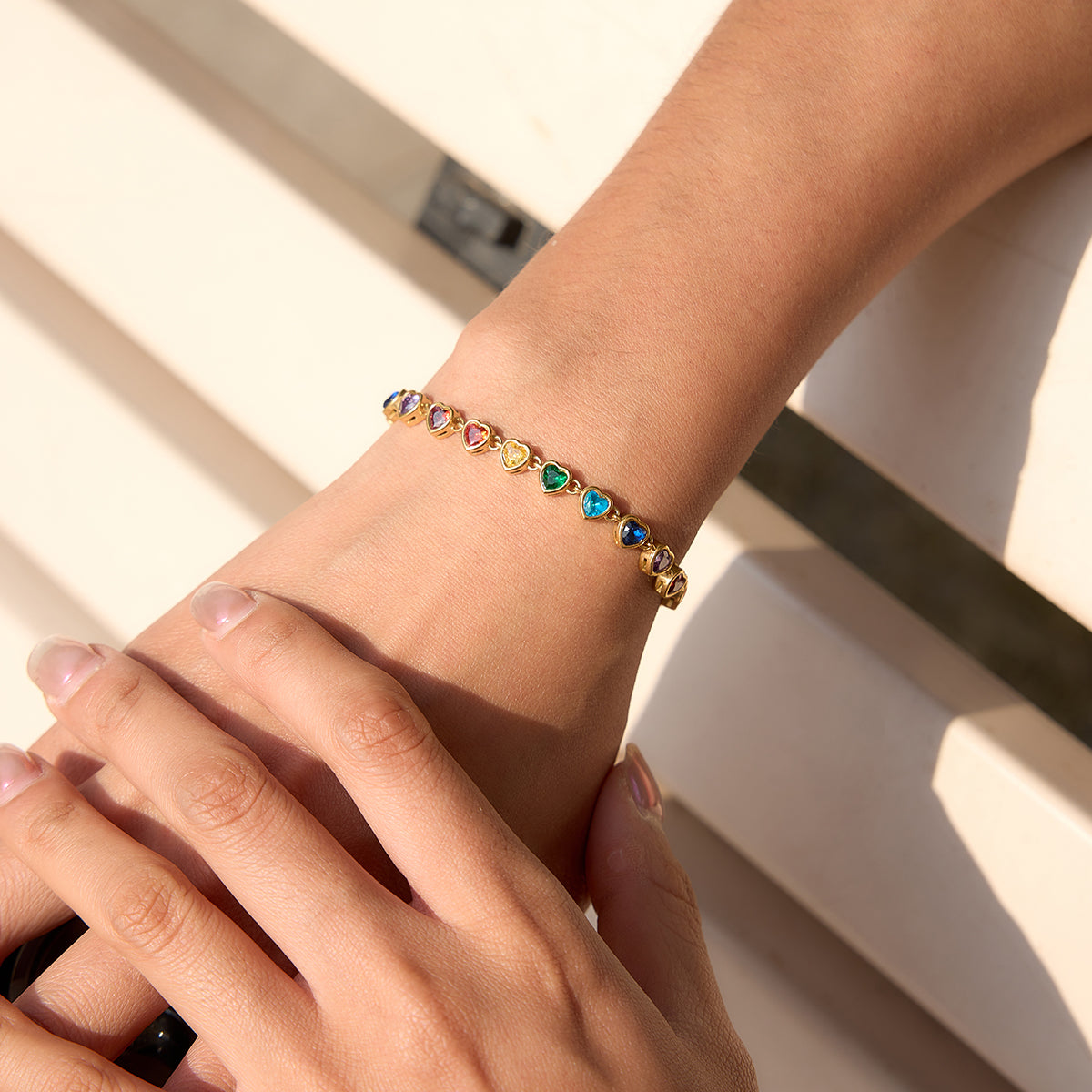 Model's hand bringing focus to multicoloured heart bracelet
