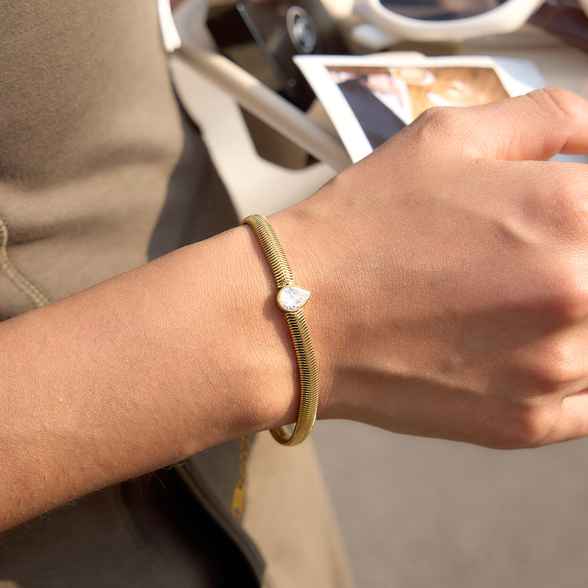 Pear shaped stone in the centre, snake chain on a person's wrist