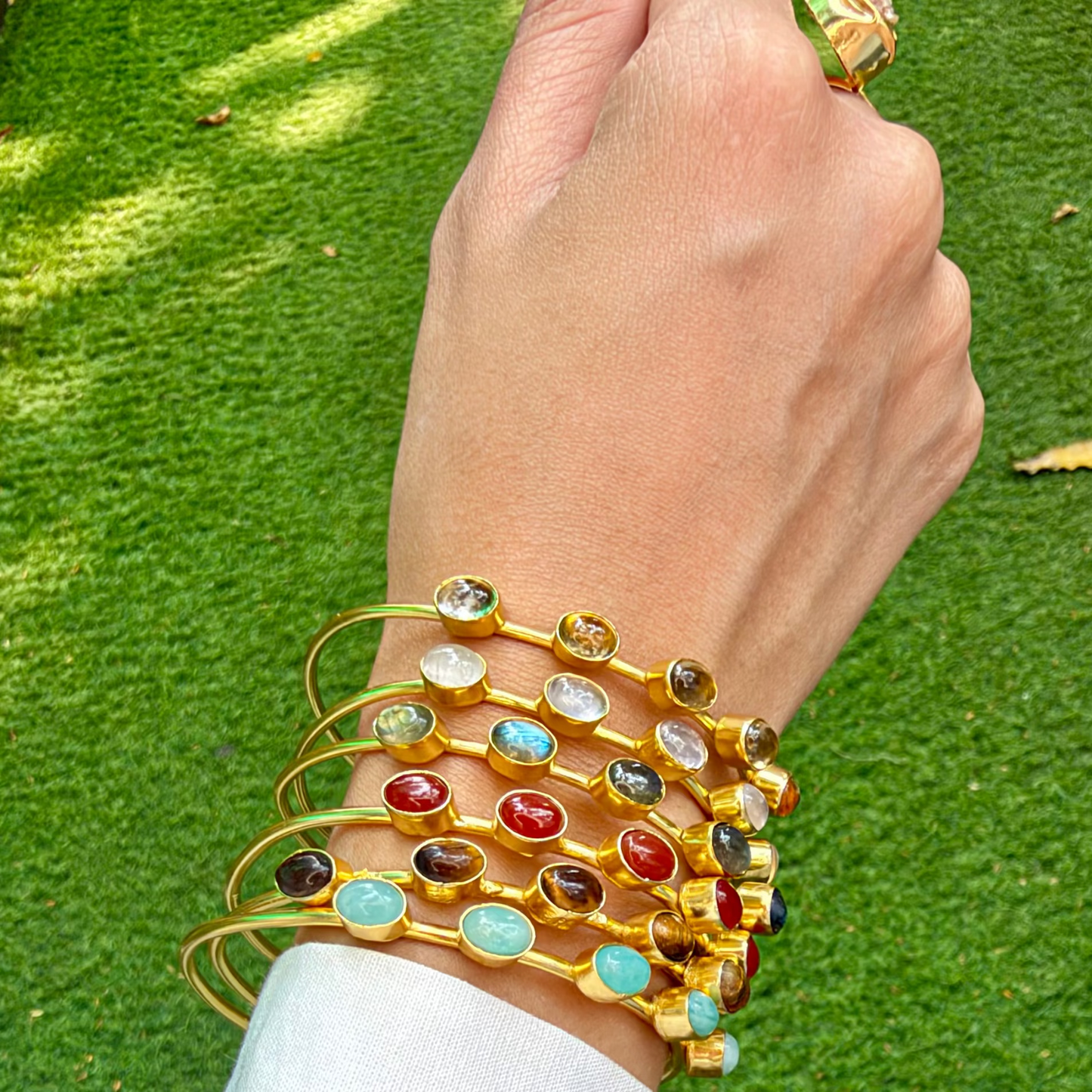 Six Cassata cuff bangles stacked on a wrist, styled with a white shirt