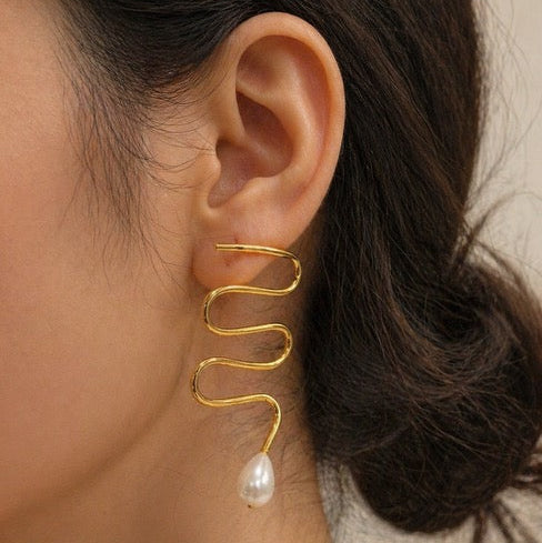 Brass sculpture earrings zig zag in shape with a pearl drop on a model's ear