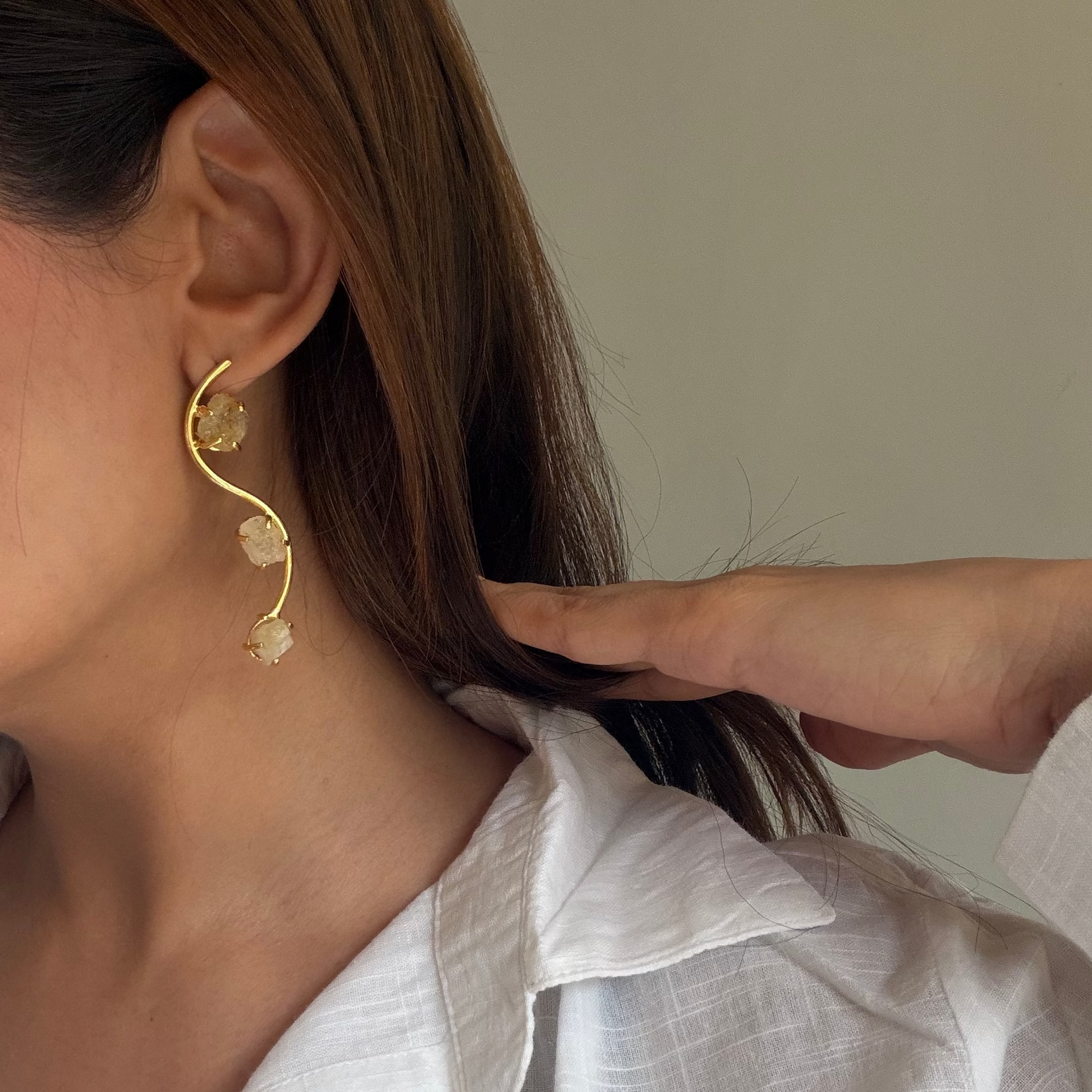 Close-up of pale yellow raw stones held in gold-finish settings on the Ladi earrings