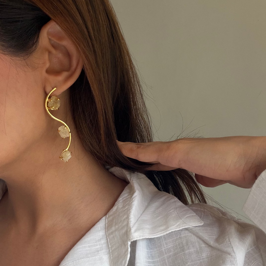 Close-up of pale yellow raw stones held in gold-finish settings on the Ladi earrings