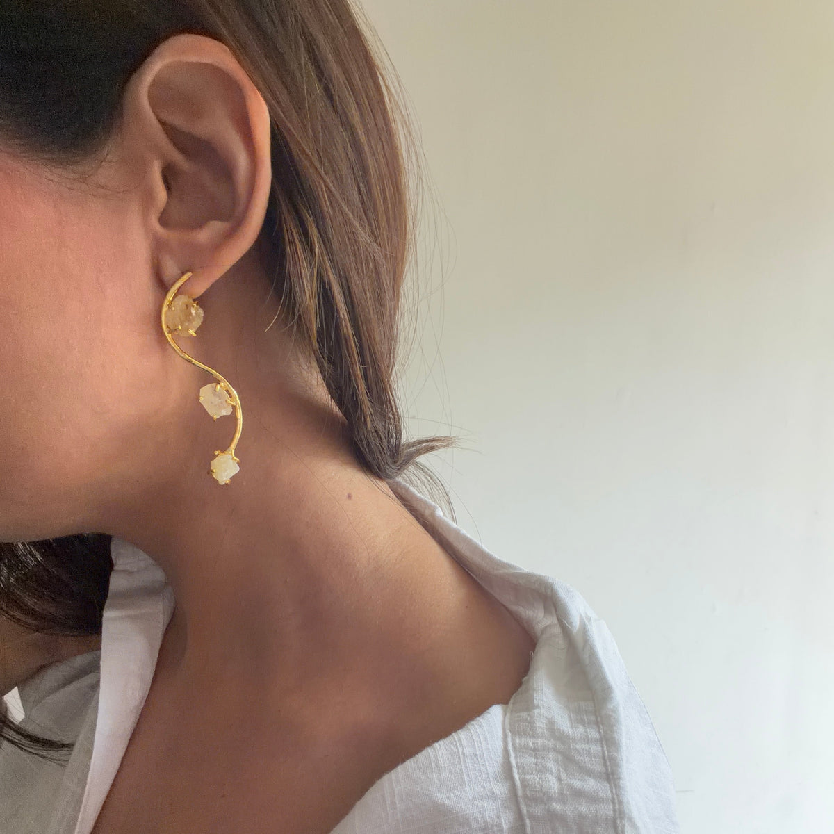 Close-up of pale yellow raw stones held in gold-finish settings on the Ladi earrings